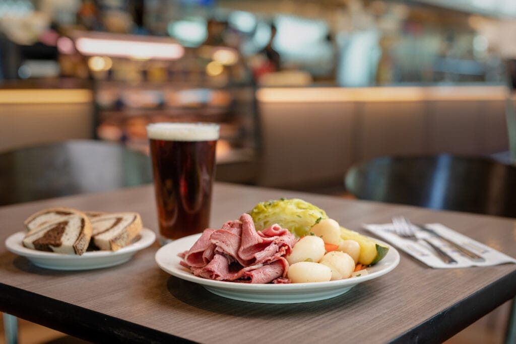 a table in a restaurant with a plate of corned beef and cabbage and beer as an example of a food photography client photoshoot