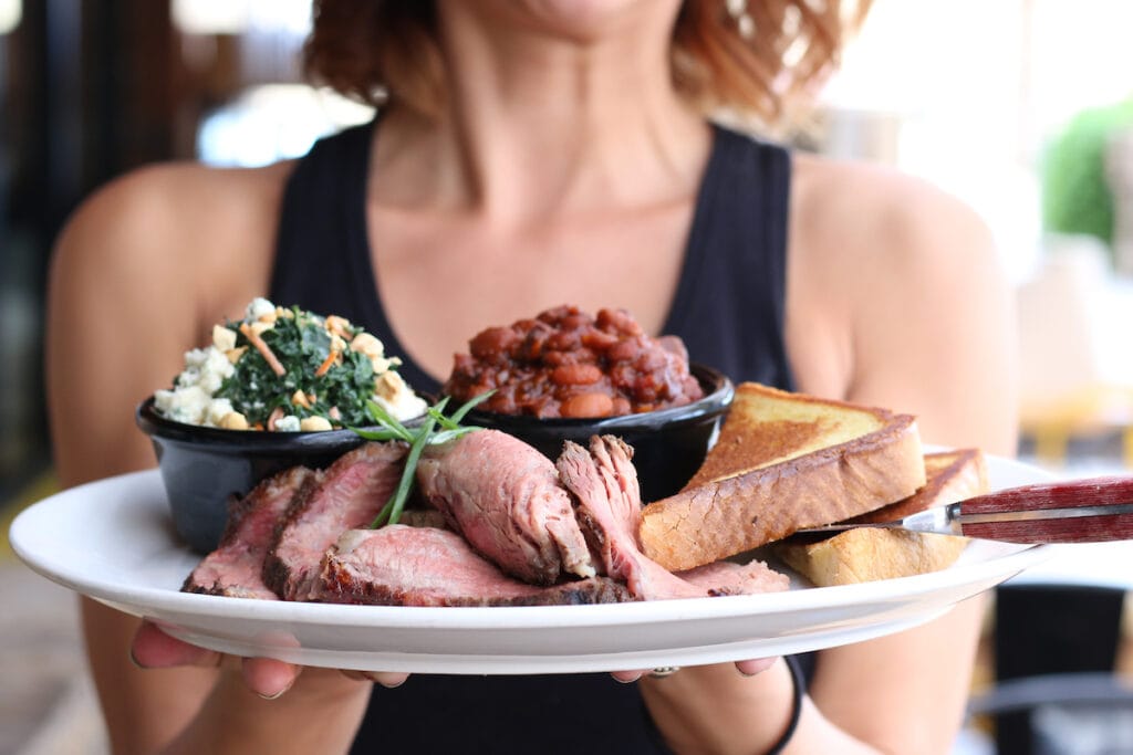 woman holding a plate of BBQ at a restaurant as an example of shooting for a restaurant client