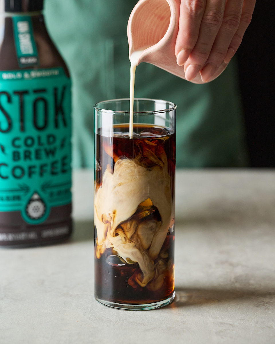 hand pouring creamer into coffee by Joanie Simon food photographer of The Bite Shot