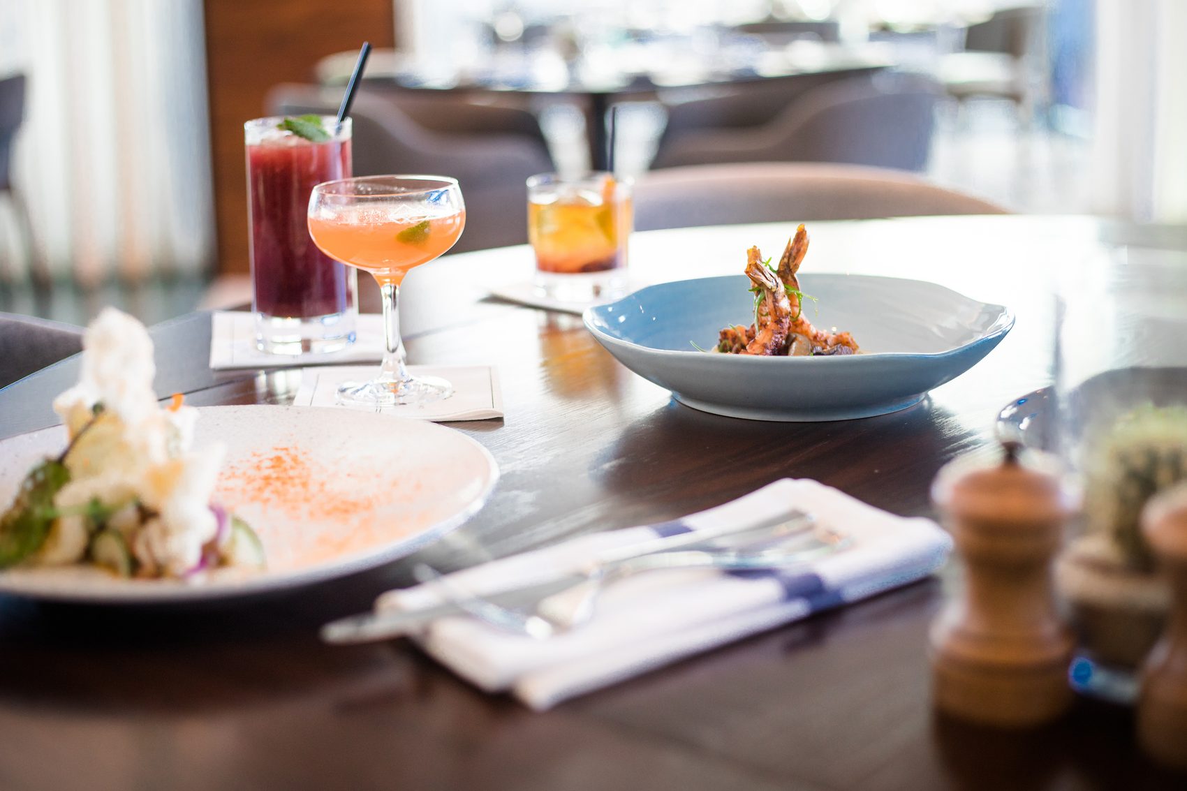 Sunlit restaurant table with cocktails and dishes