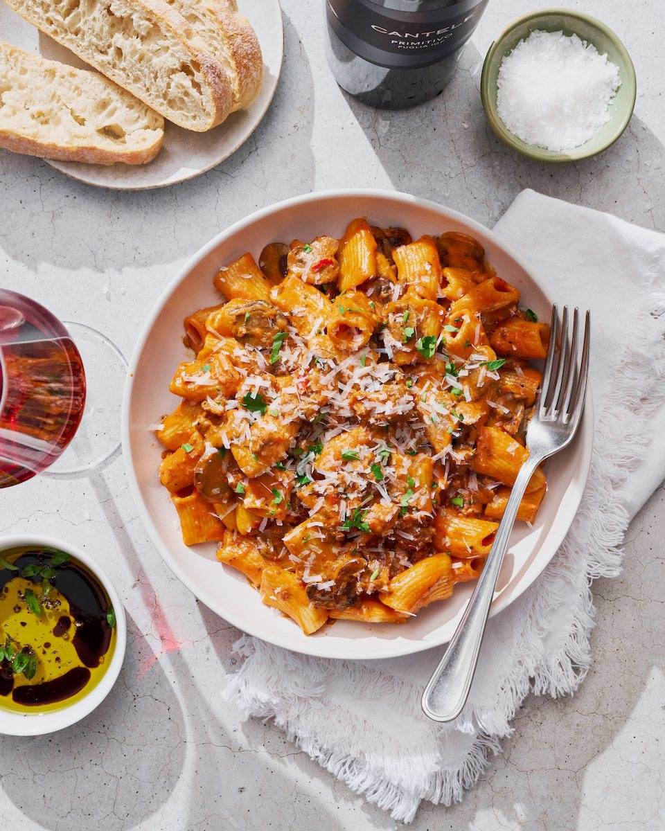 Overhead bowl of rigatoni with bread and wine