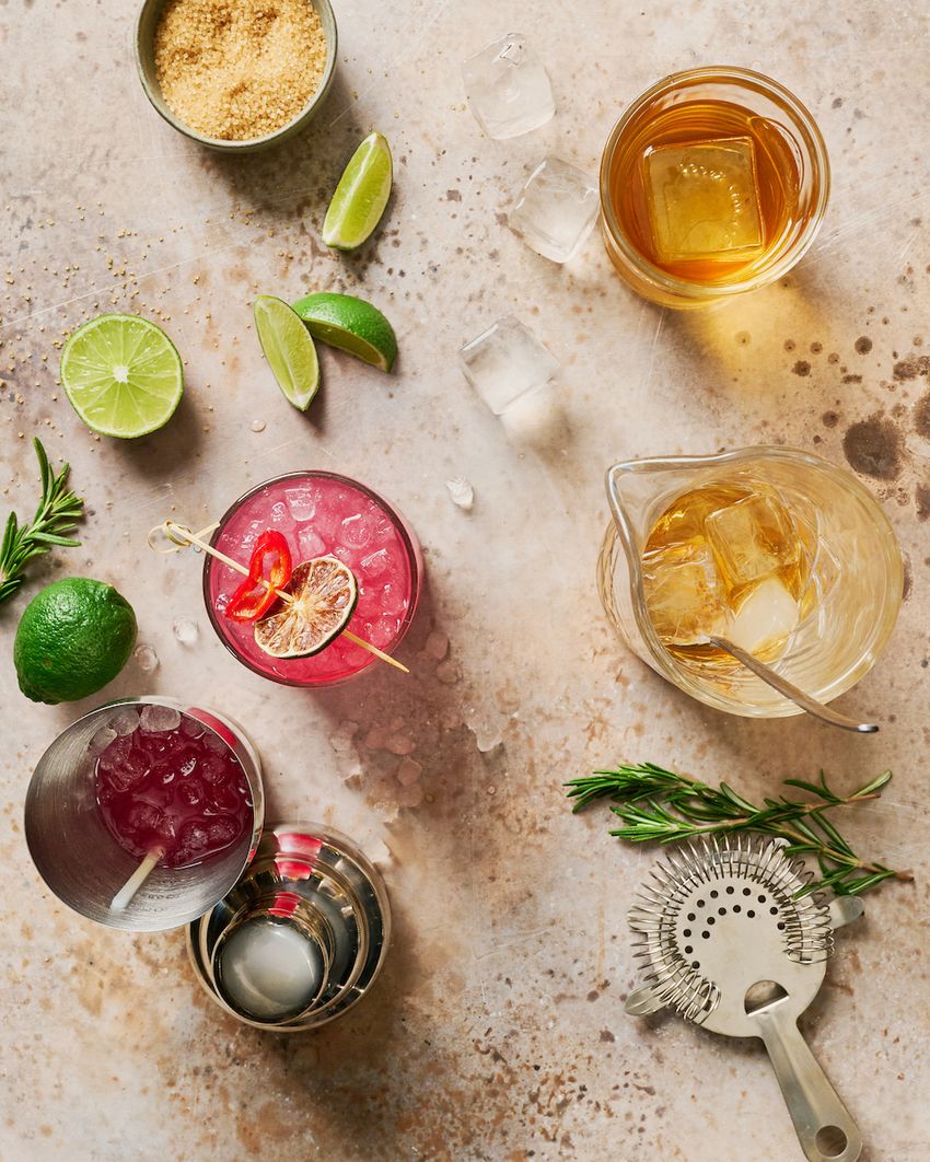 Overhead cocktail-making flatlay with citrus and tools